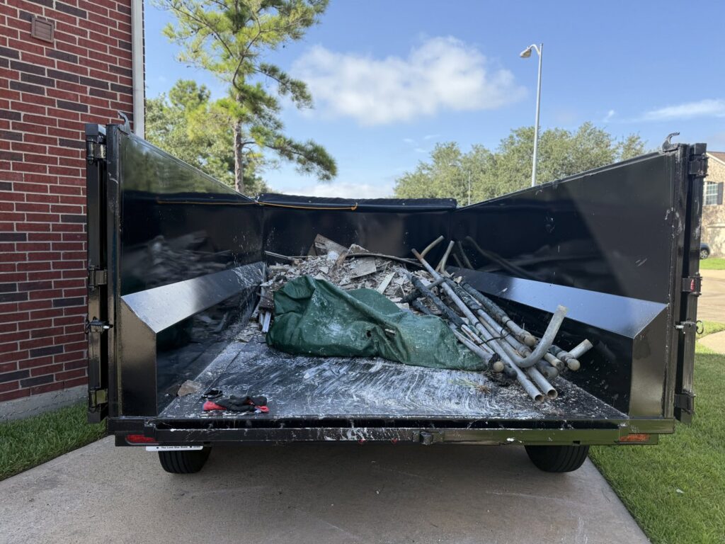 A dump trailer filled with construction debris and junk, collected by Clutch City Junk Removal in Tomball, TX.