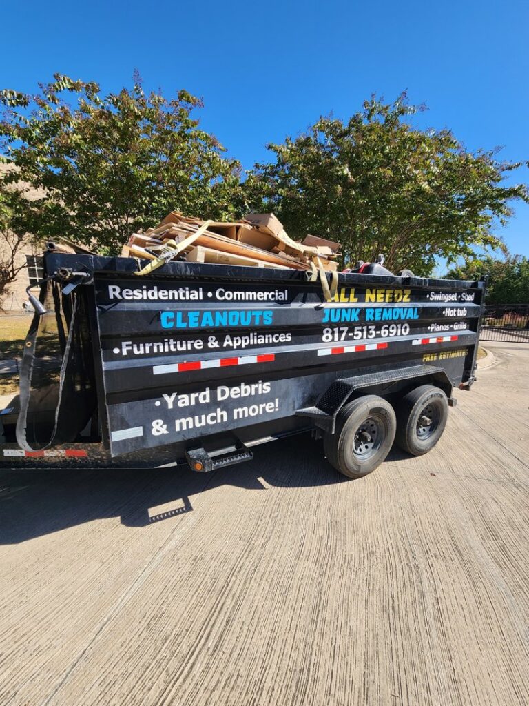 A dump trailer from All Needz Junk Removal & Hauling Service in Dallas, TX, filled with wood and construction debris.