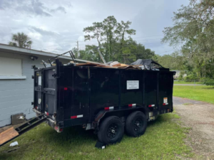 A dump trailer filled with various debris and junk, parked next to a building, handled by Jax Junkies Removal LLC in Jacksonville, FL