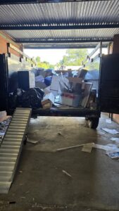 A dump trailer being loaded with boxes and bags during a junk removal service by Silverhull Junk Removal in San Antonio, TX.