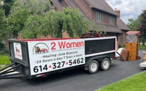 A dump trailer from 2 Women with a Pickup Truck and Trailer Too LLC parked at a residence for junk removal services in Columbus, OH.
