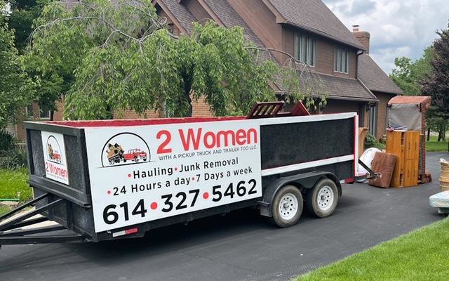 A dump trailer from 2 Women with a Pickup Truck and Trailer Too LLC parked at a residence for junk removal services in Columbus, OH.
