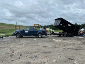 A blue pickup truck with a dump trailer unloading debris at a site, handled by Jax Junkies Removal LLC in Jacksonville, FL