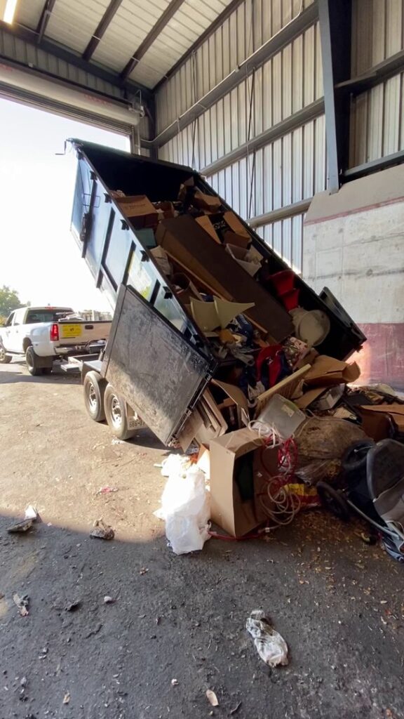 A Get Junk Help dump trailer actively unloading a large volume of junk at a disposal facility in Houston, TX.