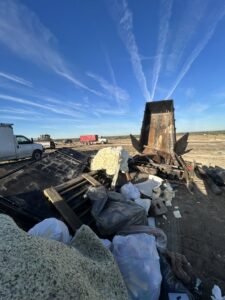 A dump trailer from 2 Women with a Pickup Truck and Trailer Too LLC unloading a large pile of mixed junk at a disposal site in Columbus, OH.