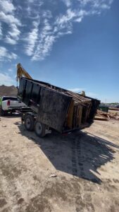 A Get Junk Help dump trailer unloading wood debris at a disposal site in Houston, TX.
