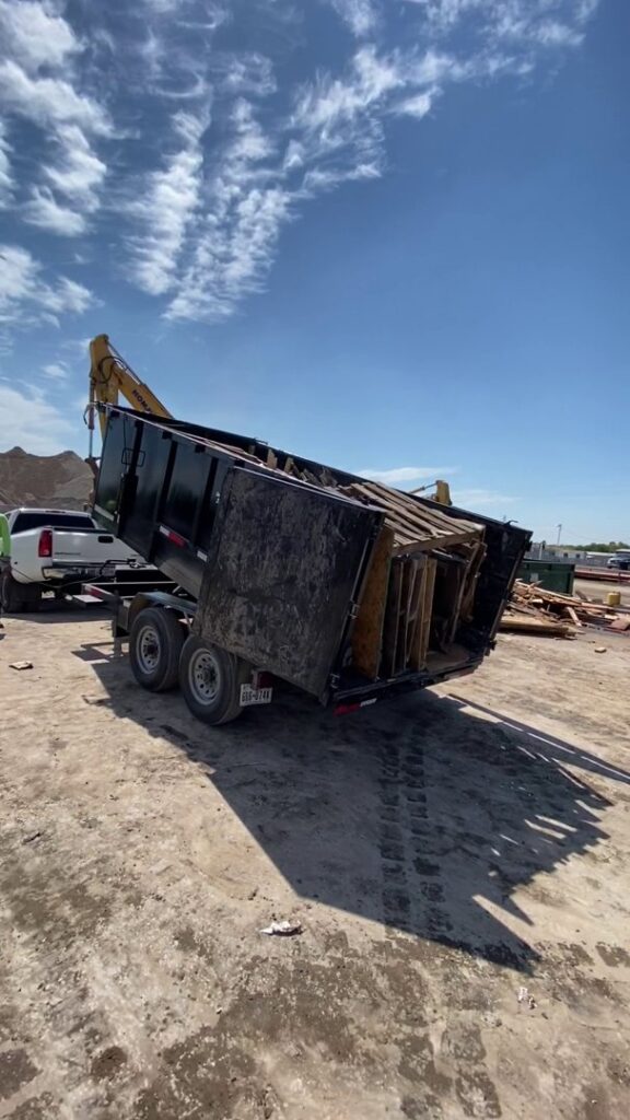 A Get Junk Help dump trailer unloading wood debris at a disposal site in Houston, TX.
