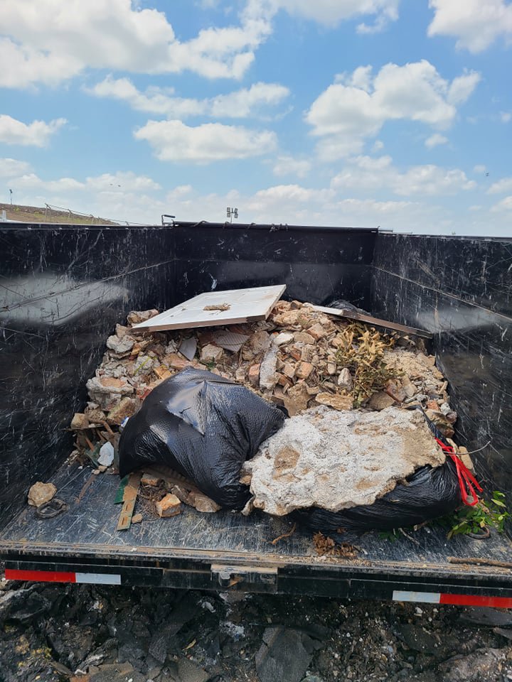 A dump trailer filled with construction debris, including bricks and concrete, handled by Eagle Junk Removal in Fort Worth, TX.