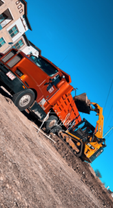 A dump truck being loaded with construction debris by a skid steer for Capital junk hauling in Austin, TX