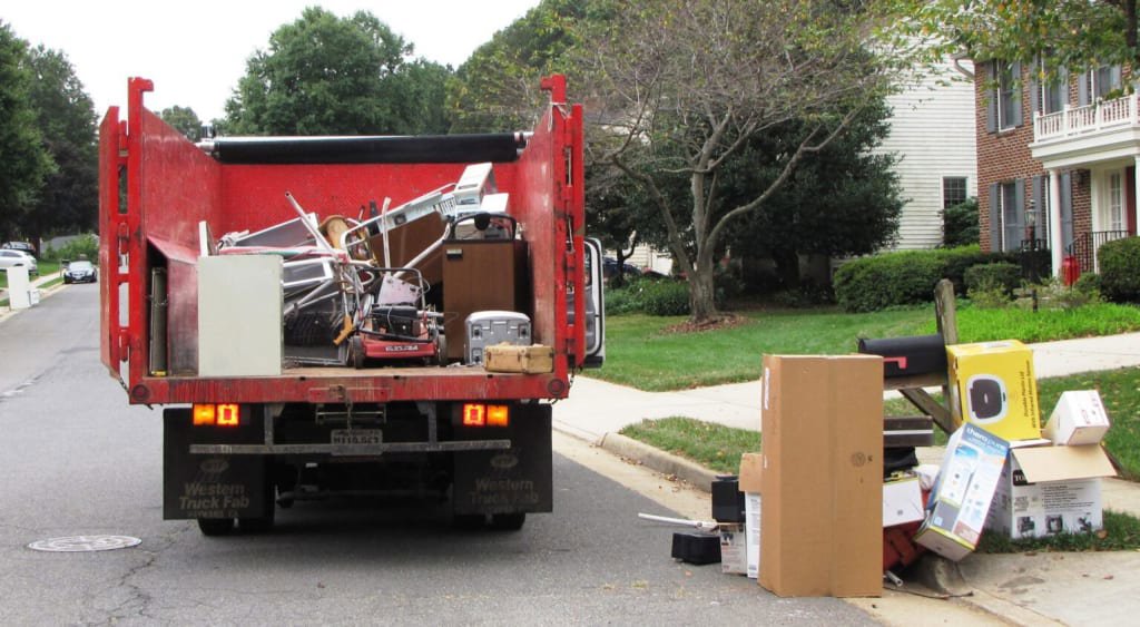 A dump truck loading household junk and debris from a residential street, demonstrating services by Epic Junk Removal SD in San Diego, CA.