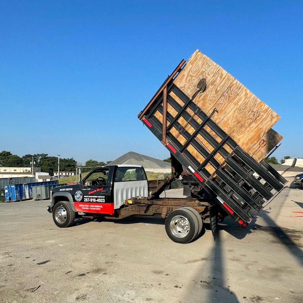 A Kay's Brothers Junk Removal dump truck with its bed raised, likely unloading junk, under a clear sky in Philadelphia, PA.