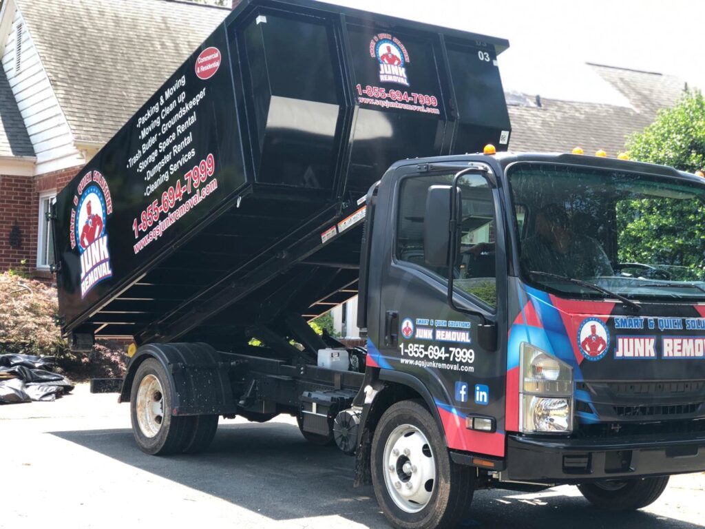 A SQS Junk Removal dumpster filled with old furniture, mattresses, and general junk after a cleanup in Charlotte, NC.