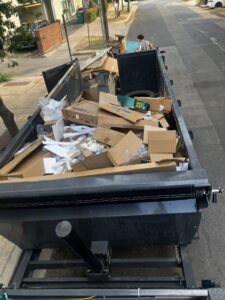 A large dumpster overflowing with cardboard boxes and packaging materials, handled by Junkie 4 Jesus Junk Removal in Austin, TX