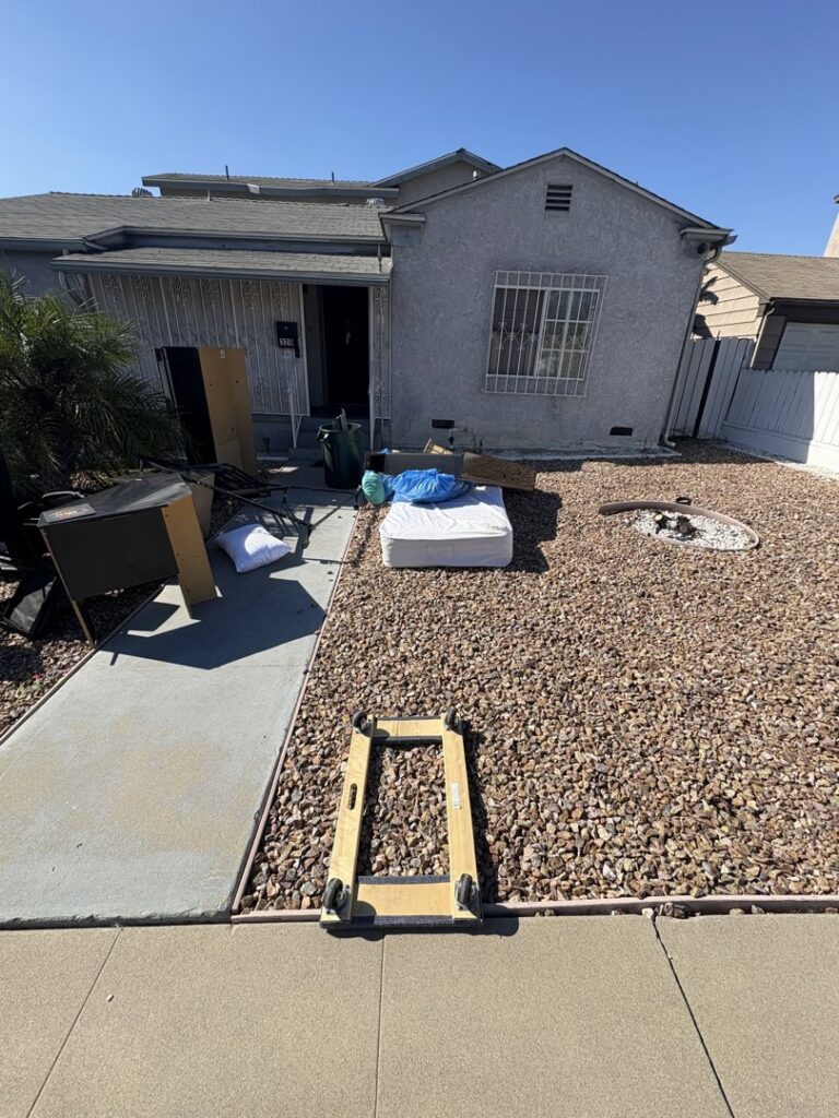 A large dumpster with the business logo, filled with household junk and furniture, ready for removal by Priority Hauling and Junk Removal San Diego.