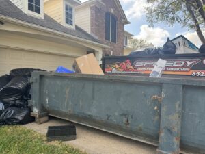 A large dumpster trailer filled with trash bags and debris from a junk removal job by Speedy Junk Removal & recycling in Houston, TX.