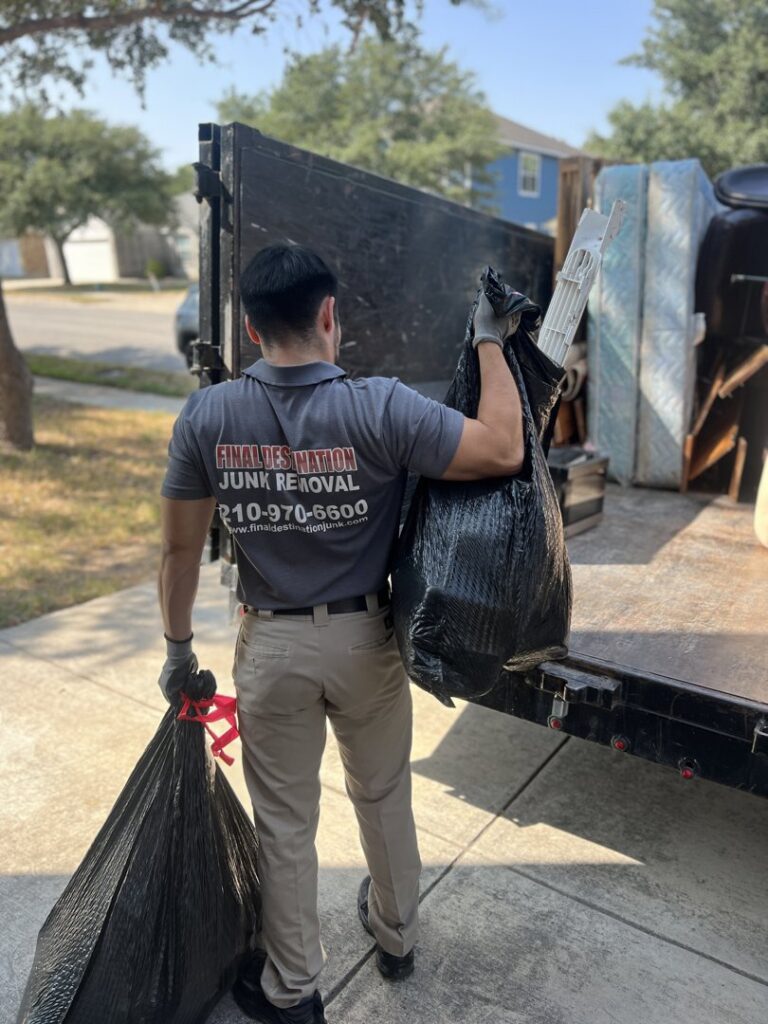 A Final Destination Junk Removal employee carrying trash bags to a junk removal trailer in San Antonio, TX.