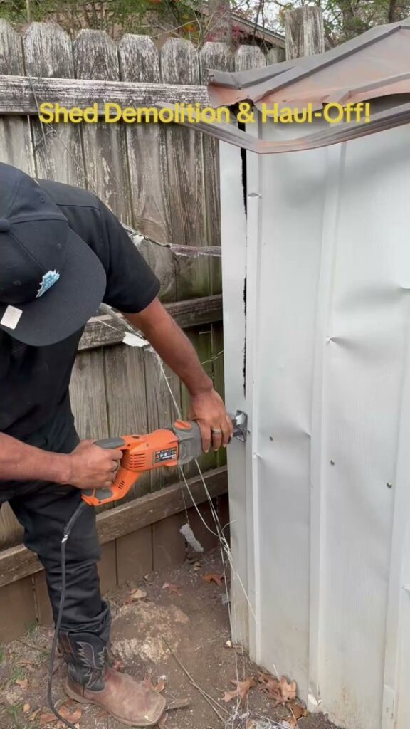 A JunkGuys Austin Junk Removal employee demolishes a metal shed with a saw, part of a shed demolition and haul-off service in Austin, TX.