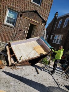 A Space Erasers Junk Removal employee working on dismantling a shed for removal in Philadelphia, PA