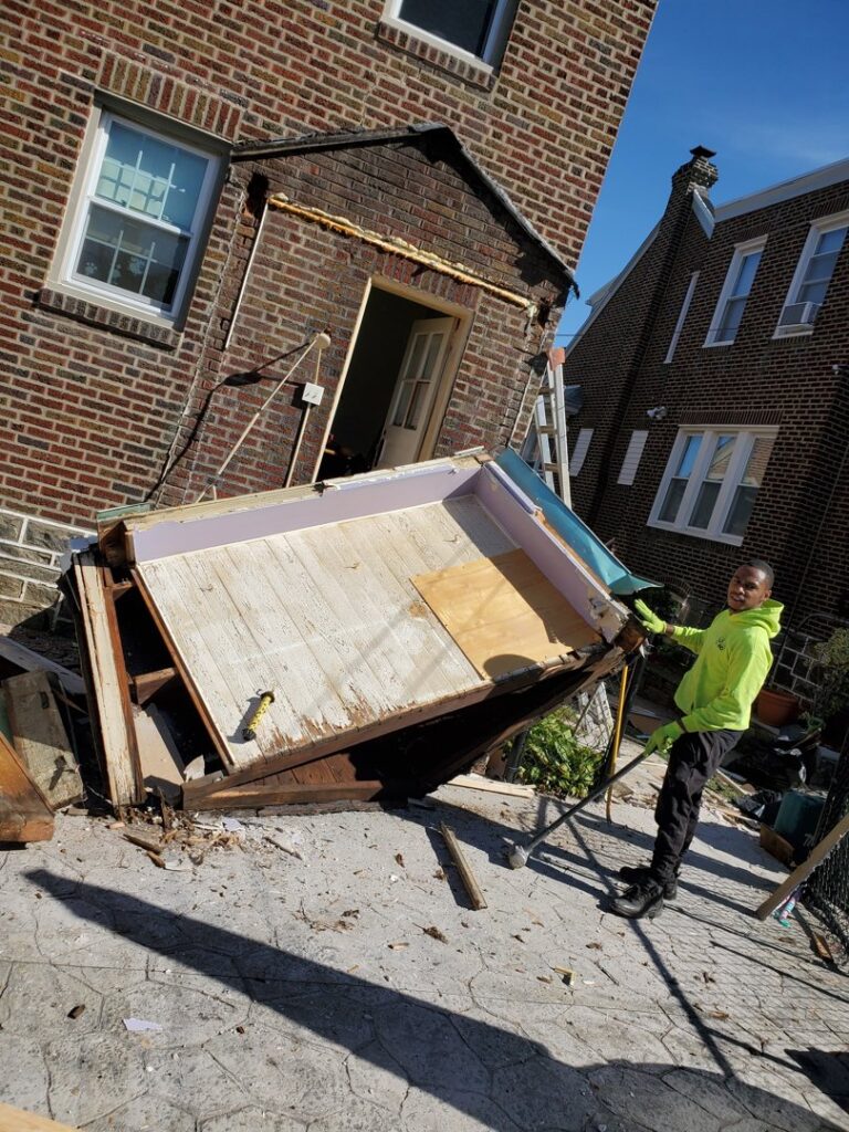 A Space Erasers Junk Removal employee working on dismantling a shed for removal in Philadelphia, PA