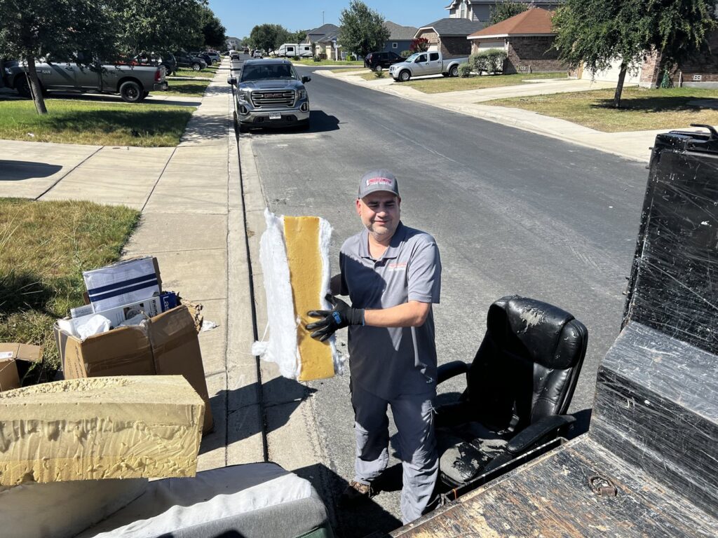 A Final Destination Junk Removal employee loading debris and an office chair into a trailer in San Antonio, TX.
