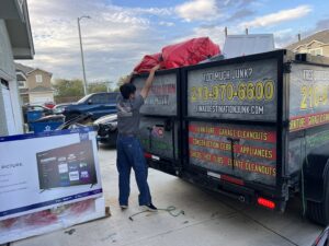 An employee of Final Destination Junk Removal loading a large bag of junk into a trailer in San Antonio, TX.