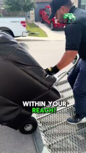 An A&J Removal Service employee loading a large, covered item onto a truck using a dolly in San Antonio, TX.