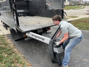 An employee loading a NordicTrack treadmill into a junk removal truck for Lug Stars Junk Removal in Columbus, OH.
