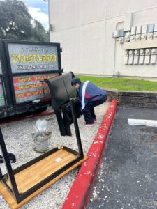 A Final Destination Junk Removal employee moving a piece of furniture towards a junk removal trailer in San Antonio, TX.