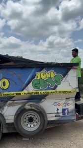 A JunkGuys Austin Junk Removal employee stands next to a loaded junk removal trailer, ready for transport in Austin, TX.