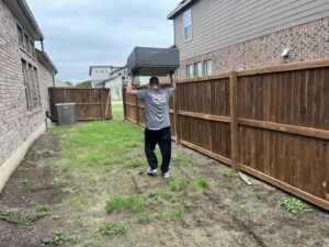 A Final Destination Junk Removal employee carrying outdoor furniture for removal in a backyard in San Antonio, TX.