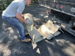 An employee rolling up old carpet for removal by Lug Stars Junk Removal in Columbus, OH.