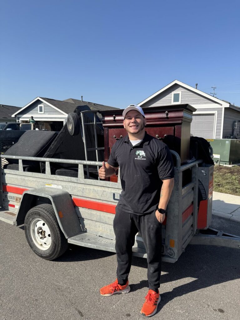An A&J Removal Service employee giving a thumbs up next to a trailer loaded with furniture after a junk removal job in San Antonio, TX.