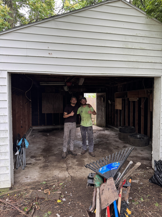 Two Load & Go Hauling Junk Removal employees giving thumbs up after clearing out a garage in Grove City, OH.