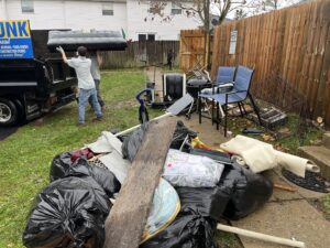 Employees loading an inflatable mattress into a truck, with a large pile of junk in the foreground for Lug Stars Junk Removal in Columbus, OH.