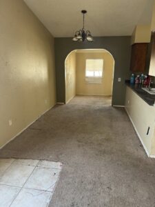An empty room with worn carpet and tile, indicating a space ready for cleanout and junk removal by North Valley Junk Removal in Phoenix, AZ.