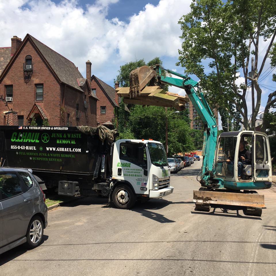 An excavator loading construction debris and junk into a G.I. HAUL truck during a large-scale removal job in Austin, TX.