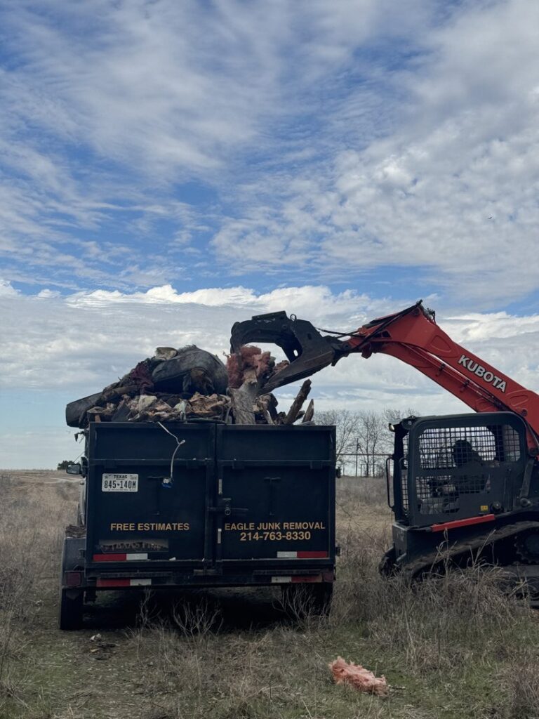 An excavator loading a junk removal trailer with mixed debris for Eagle Junk Removal in Fort Worth, TX.