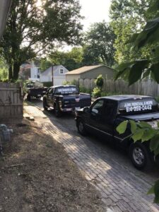 A fleet of Junk Removal and More LLC trucks parked on a residential driveway in Columbus, OH, ready for service.