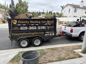 A residential front yard with a mattress, wood, and other debris awaiting junk removal by Priority Hauling and Junk Removal San Diego, CA.