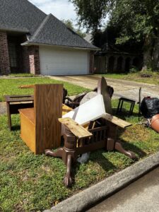 Furniture and various household items piled on a residential lawn, ready for junk removal by Handymen Junk Removal in Houston, TX.
