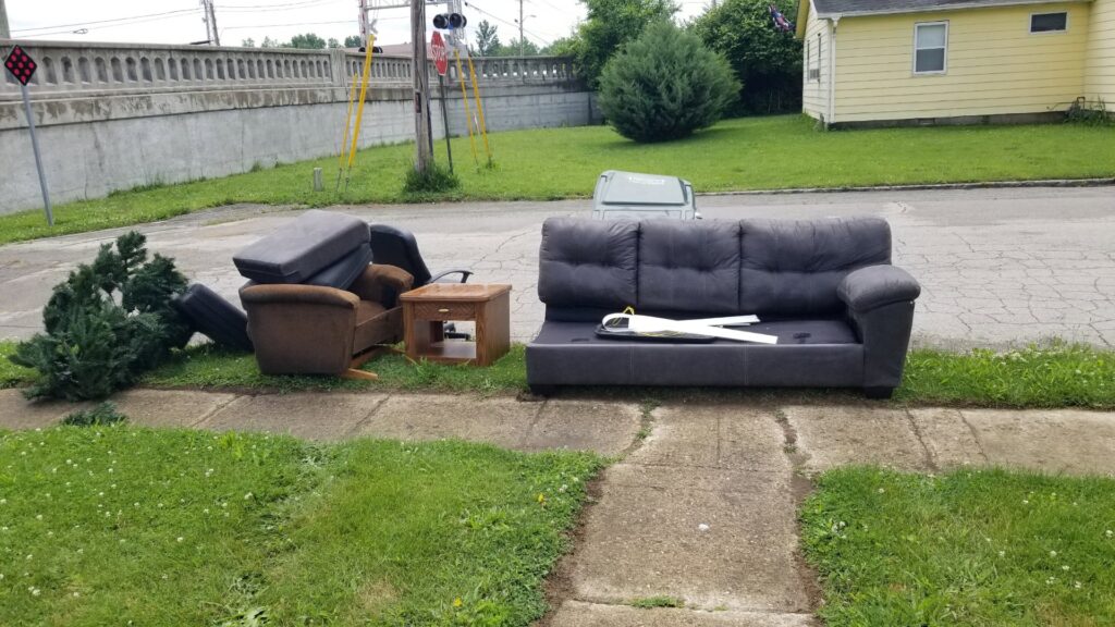 Old furniture, including a couch and armchair, placed curbside for junk removal by Indy Trash Guy in Fortville, IN.