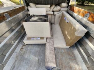A junk removal truck bed filled with old furniture and a rolled rug by The Mess Haul in Jacksonville, FL.