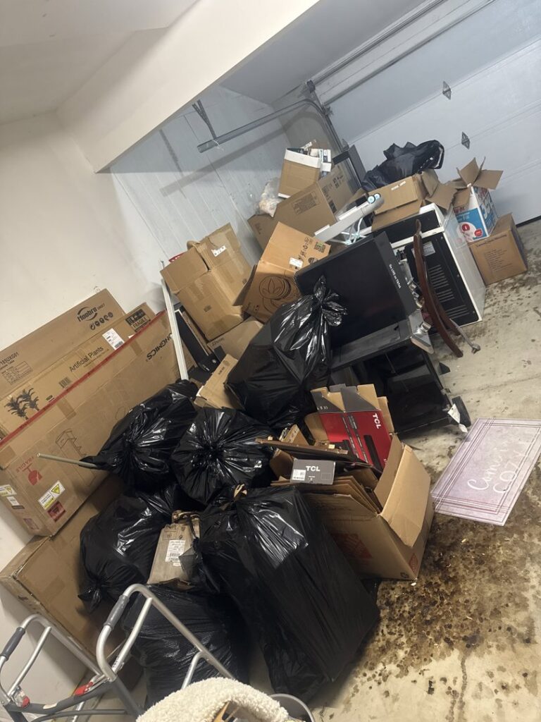 A garage filled with boxes, trash bags, and old electronics, ready for cleanout by Junk Fellas LLC in Columbus, OH.