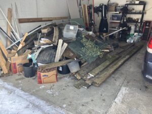 A cluttered garage with a large pile of junk and debris, ready for cleanout by We Haul It Cleaning Service LLC in Canal Winchester, OH.