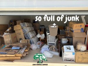 A cluttered garage completely full of boxes, furniture, and various junk items before a cleanout by A&J Removal Service in San Antonio, TX.