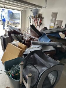 A garage filled with various items for junk removal, with a 1-800-GOT-JUNK? truck waiting outside in Fort Worth, TX.