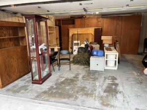 Various furniture and clutter in a garage, indicating a junk removal job by Hud's Haul Away Junk Removal & Demolition in Fort Worth, TX.