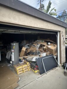 A garage overflowing with cardboard boxes, a water heater, and miscellaneous junk, ready for Crisan Junk Removal in San Diego, CA.