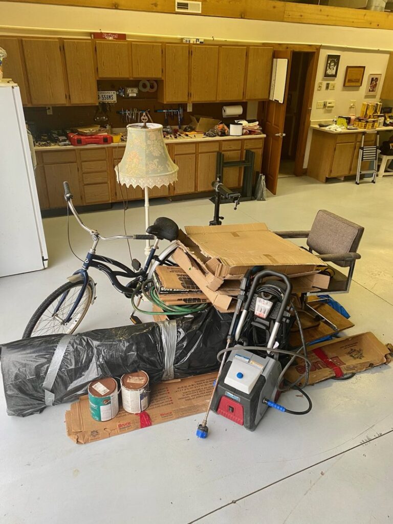 A pile of various items including a bicycle, boxes, and tools in a garage or workshop, ready for junk removal by ABC Junk Removal & Hauling in Westfield, IN.