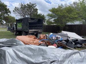 A G.I. HAUL truck parked next to a large pile of residential junk and debris for removal in Austin, TX.